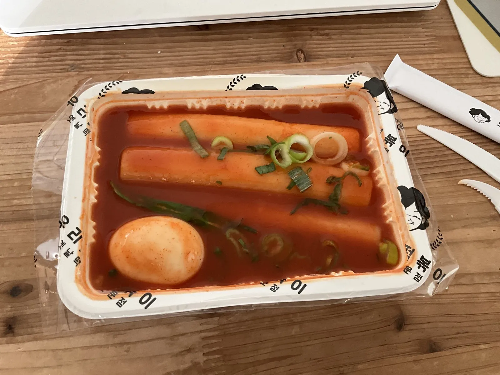 A bowl of Korean tteokbokki — chewy garaetteok rice cakes in a glossy red sweet-and-spicy gochujang sauce